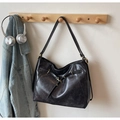 Schwarze Tote-Bag aus Öl-Wachs-Leder mit goldener Schnalle an einem Holzhaken - Dunkelbraun