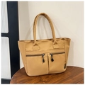 Dettaglio della borsa tote in nylon kaki con due tasche frontali su un tavolo in legno - Marrone