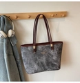 Detalle del bolso tote gris con patrón de mármol colgado en un gancho de madera y hebilla - Negro