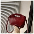 Macro shot of glossy red faux leather handbag with cutout handle and brand lettering - Red
