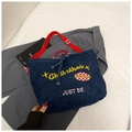 Detail der blauen Denim-Tasche mit rotem Gurt und Stickerei auf einem grauen Jackett - Dunkelblau