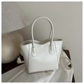 Detail of cream white bucket bag featuring wave-edge design and embossed fashion text - White