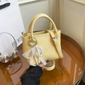 Bright yellow pebbled leather bucket bag with pearl lace bow charm and shoulder strap - With Pendant / Yellow
