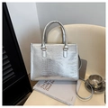 Nahaufnahme der silbernen Tasche mit Krokostruktur und Riemen auf einem Stuhl - Silber