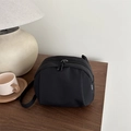 Minimalist black nylon crossbody bag with dual zipper closure and white woven brand label - Black