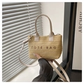 Détail d'un sac cabas en paille tressée avec broderie marron et bandoulière en cuir élégante - Blanc Cassé