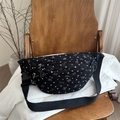 Black canvas chest bag with white heart prints and adjustable strap on a vintage chair - Black