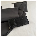 Detail of long black snake-patterned wallet with gold zipper on a gray blazer background - Black