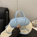 Light blue patent leather handbag with adjustable strap shown in a lifestyle setting - Blue