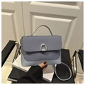 Detail of grey-blue woven handbag featuring a silver U-shaped clasp and leather strap - Black