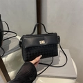 Sac à main noir structuré avec motif pied-de-poule et poignée sur une table blanche - Noir
