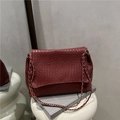 Sac bandoulière bordeaux tissé avec chaîne en métal argenté sur un socle blanc - Rouge