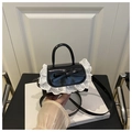Detail of black faux leather mini bag with white lace trim and bow accent held by hand - Black