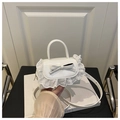 Detail view of white mini handbag featuring 3D leather bow and delicate lace trim edges - White