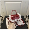 Close-up of red mini handbag with leather bow detail and white lace embroidery trim - Red