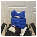 Makro-Detail der königsblauen Stepptasche mit großer Dekoschleife und bauschiger Textur - Blau