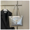Detail of silver metallic tote bag featuring a gold deer charm and chain shoulder strap - Silver