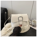 Primo piano della borsa a tracolla bianca minimalista con fibbia argento su legno scuro - Bianco