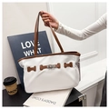 Detailed view of white tote bag with brown leather trim and silver metal twist lock - White