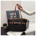 Close-up of black nylon tote bag with brown leather handles and classic metal buckle - Black
