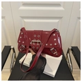 Detailaufnahme der dunkelroten Lackledertasche mit silbernen Nieten und Metallschnalle - Rot