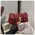 Detail der burgunderroten Tasche mit Kroko-Prägung, goldenem Drehverschluss und Schulterriemen - Rot