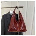 Détail d'un grand cabas en cuir rouge vin brillant avec une texture lisse et polie - Style Brillant / Rouge