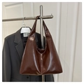 Grand sac cabas hobo marron en similicuir brillant suspendu à côté d'un blazer gris - Style Brillant / Marron