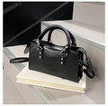Dettaglio della borsa nera con borchie argentate e manici circolari su supporto bianco - Nero