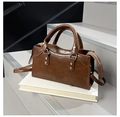 Dettaglio di borsa vintage in pelle marrone con finiture argentate sopra un libro - Marrone