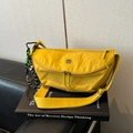Detail van een gele halvemaanvormige nylon crossbodytas met dubbele rits en een bedeltje - Geel met hanger