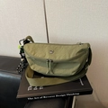 Detail van olijfgroene nylon crossbodytas met dubbele rits en geruite bedelhanger - Grijsgroen Met Hanger