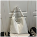 Minimalist white leather tote bag with a soft triangular silhouette on a book - Cream White (2015)