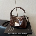 Deep brown patent leather handbag with a top handle and shoulder strap on a book base - Brown