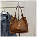Dettaglio di una borsa tote in pelle PU marrone lucida con trama del materiale e capienza - Marrone