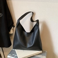 Elegante borsa tote in pelle intrecciata nera da donna su una valigia argento da viaggio - Nero