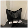 Detail view of a black faux leather tote bag with Fashion & Bags text on a chair - Black