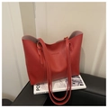 Detail view of red tote bag with dual straps resting on a sleek black leather seat - Red