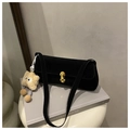 Detail of black suede baguette bag with gold buckle and star charm on grey books - With Pendant / Black
