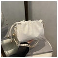 Bolso tipo cubo blanco plisado con correa de cadena sobre fondo de libro gris - Blanco
