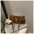 Close-up of brown suede shoulder bag with gold metal buckle and plush monster charm - With Pendant / Brown