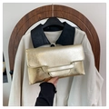 Detail of a gold metallic envelope clutch with pleated texture and handle shown with an outfit - Gold
