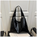 Detail of a large black glossy leather hobo tote bag displayed on a modern chair - Glossy Black (2015)