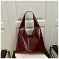Detail of burgundy glossy tote bag with golden bee emblem on a dark seat background - Burgundy Bee Buckle (2015)