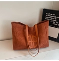 Detail of caramel brown suede tote bag featuring a round embossed logo and leather straps - Brown