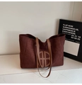 Detail of suede tote bag showing dark brown matte texture and circular leather logo - Brown