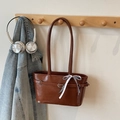 Chic retro brown leather tote bag with a checkered bow tie hanging on a wooden rack - Brown