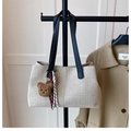 Detail of canvas tote bag with black leather straps and a brown plush bear charm accessory - Beige and Black (with Charm)