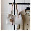 Detail of off-white woven tote bag featuring leather handles and brown teddy bear charm - Beige and Khaki (with Charm)