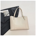 Detail of elegant beige PU leather tote bag with golden logo and metallic buckle accents - White